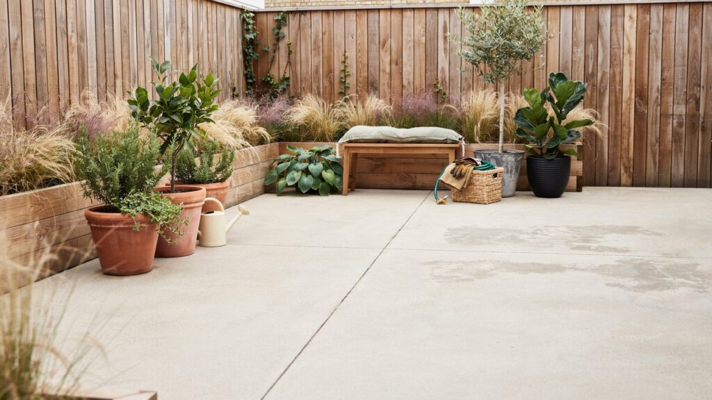 Small concrete garden made nicer with seating, planters, outdoor rug and warm lighting - concrete planters